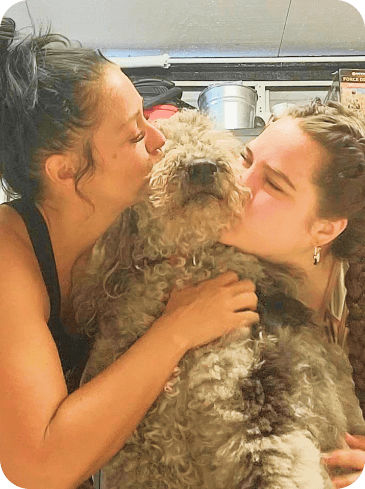  Curly Haired Dog Hugged by Two Women 